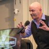 Keynote speaker Kevin Bulmer on stage at a Little Engines live event in a powerful stance, illustrating resilience by pushing back against opposing forces.