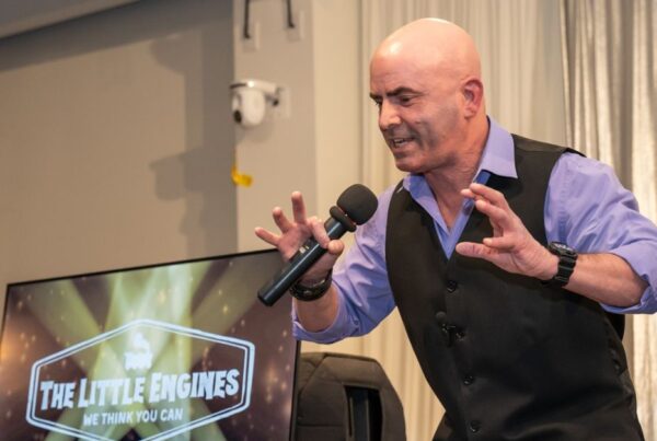 Keynote speaker Kevin Bulmer on stage at a Little Engines live event in a powerful stance, illustrating resilience by pushing back against opposing forces.