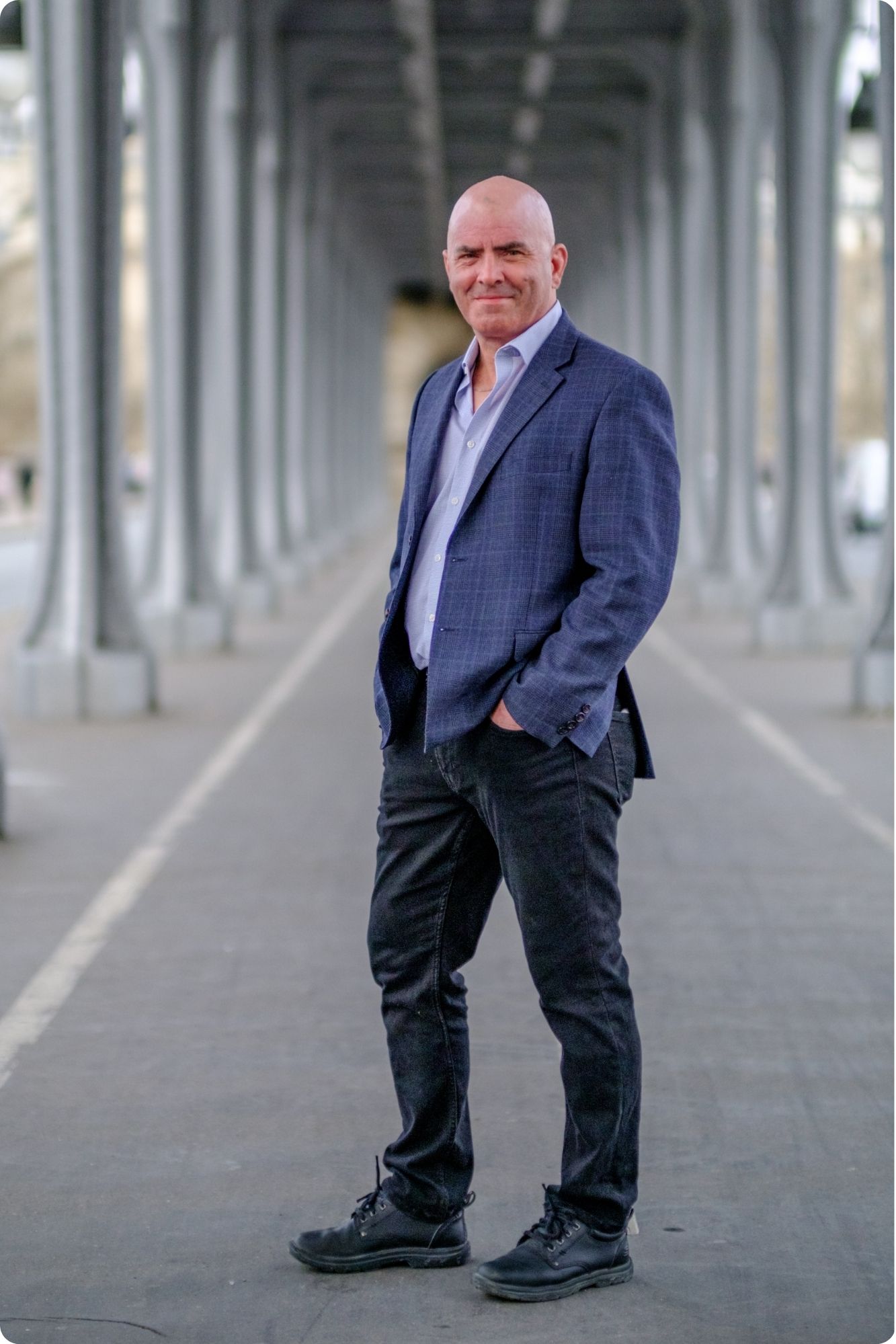 Kevin Bulmer (KB) standing casually under a train overpass in Paris, France, embodying the relaxed, authentic, and adventurous spirit of the No Schedule Man brand.