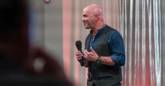 Kevin Bulmer speaking on stage during a keynote address about navigating change and leadership.